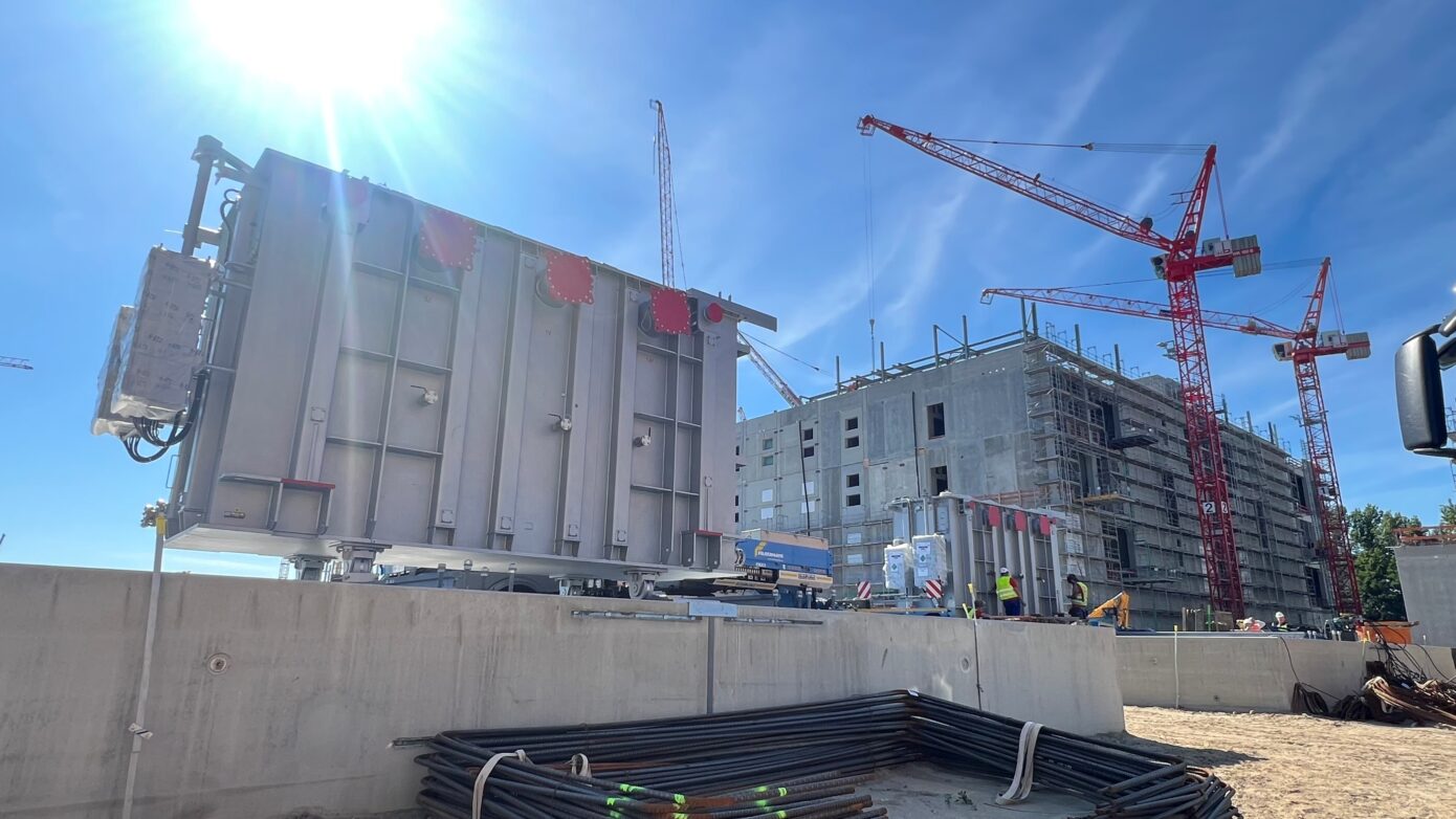 Bauprojekt mit Kränen und Baustellenmaschinen unter klarem Himmel.