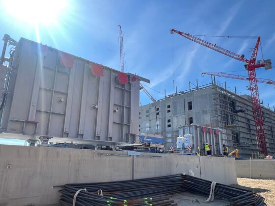 Bauprojekt mit Kränen und Baustellenmaschinen unter klarem Himmel.