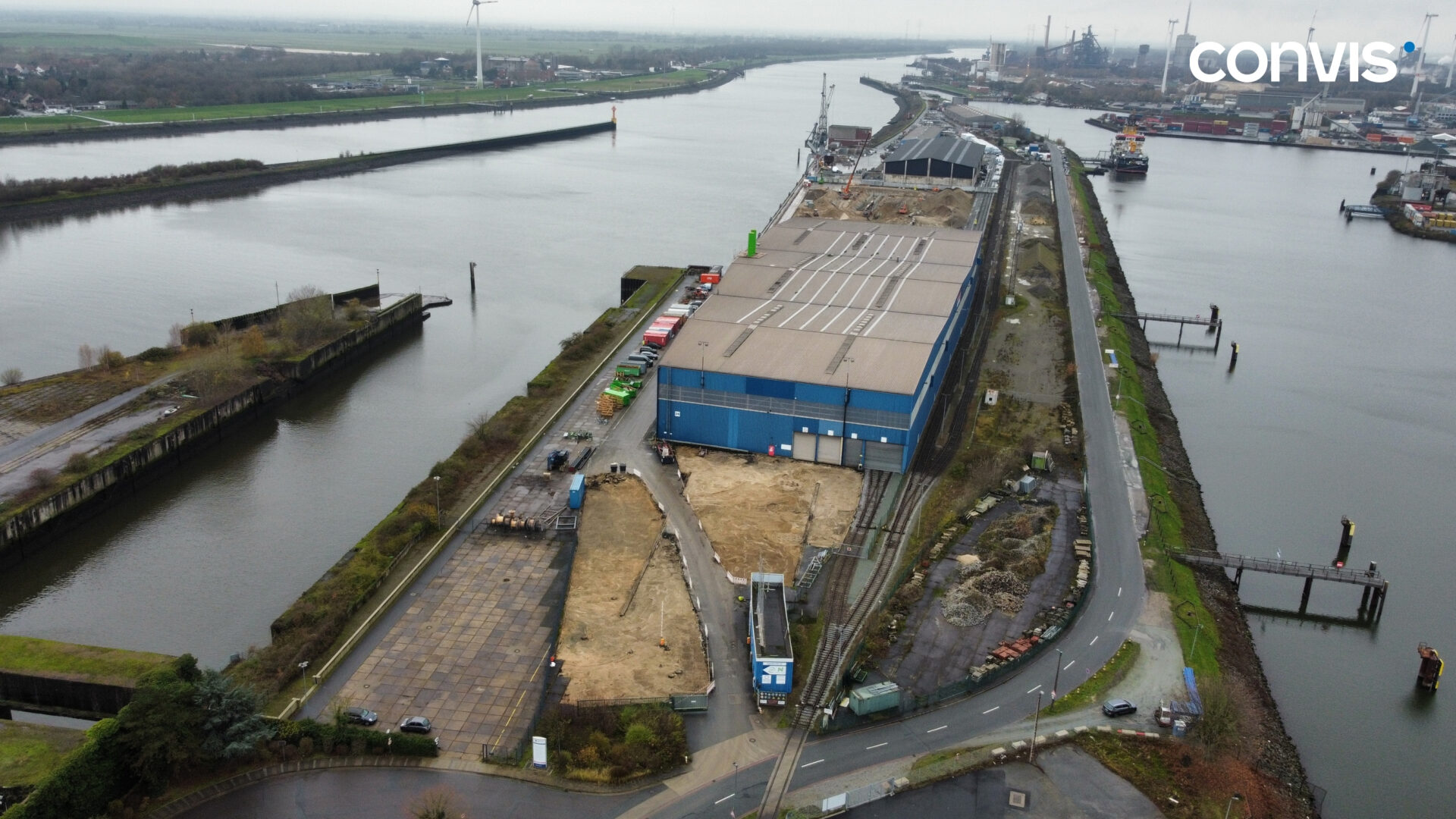 Luftaufnahme eines Hafens mit Lagergebäude und Wasserwegen in Industriegebiet.