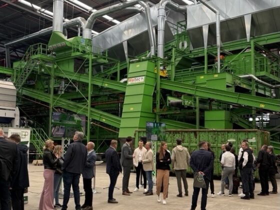 Besuchergruppe in einer modernen Recyclinganlage mit grüner Maschinenausstattung.