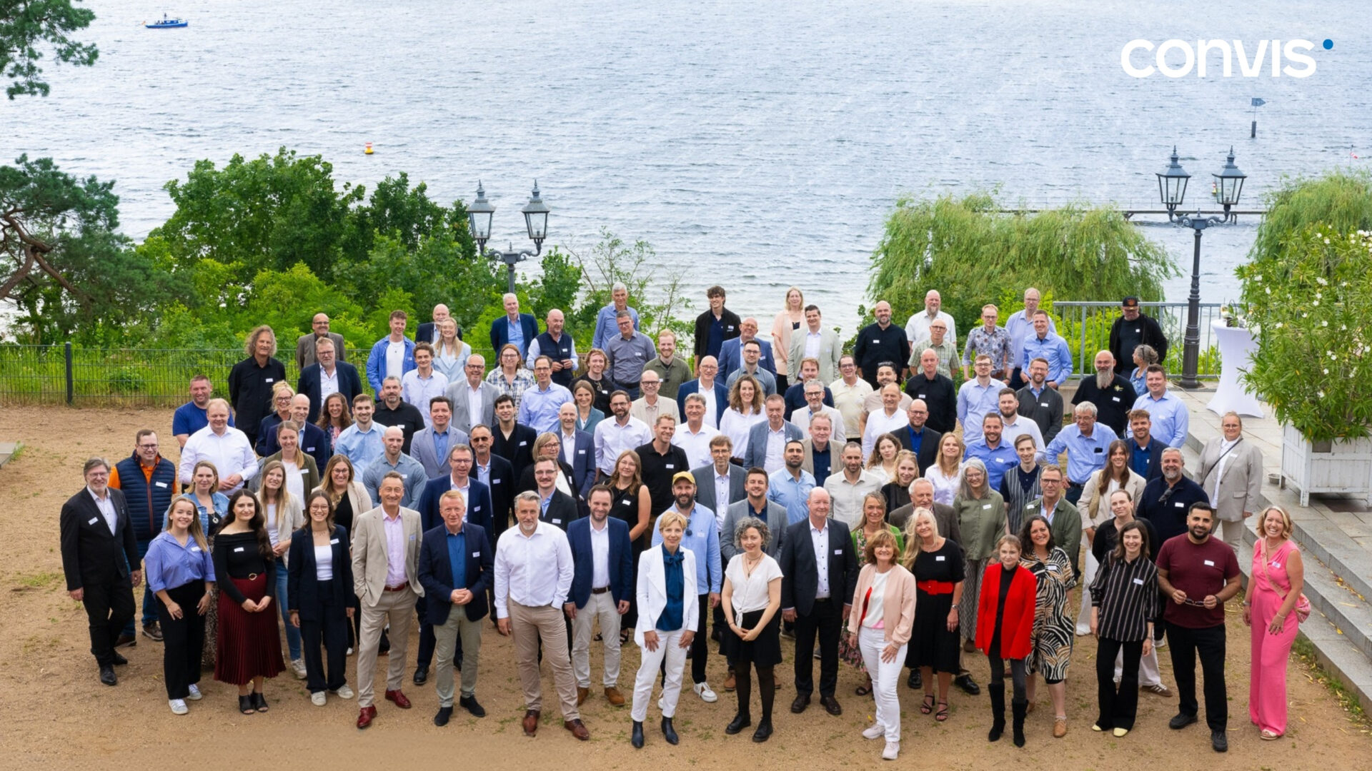 Gruppenfoto von Convis Mitarbeitern am Wasser, umgeben von Natur und Bäumen.