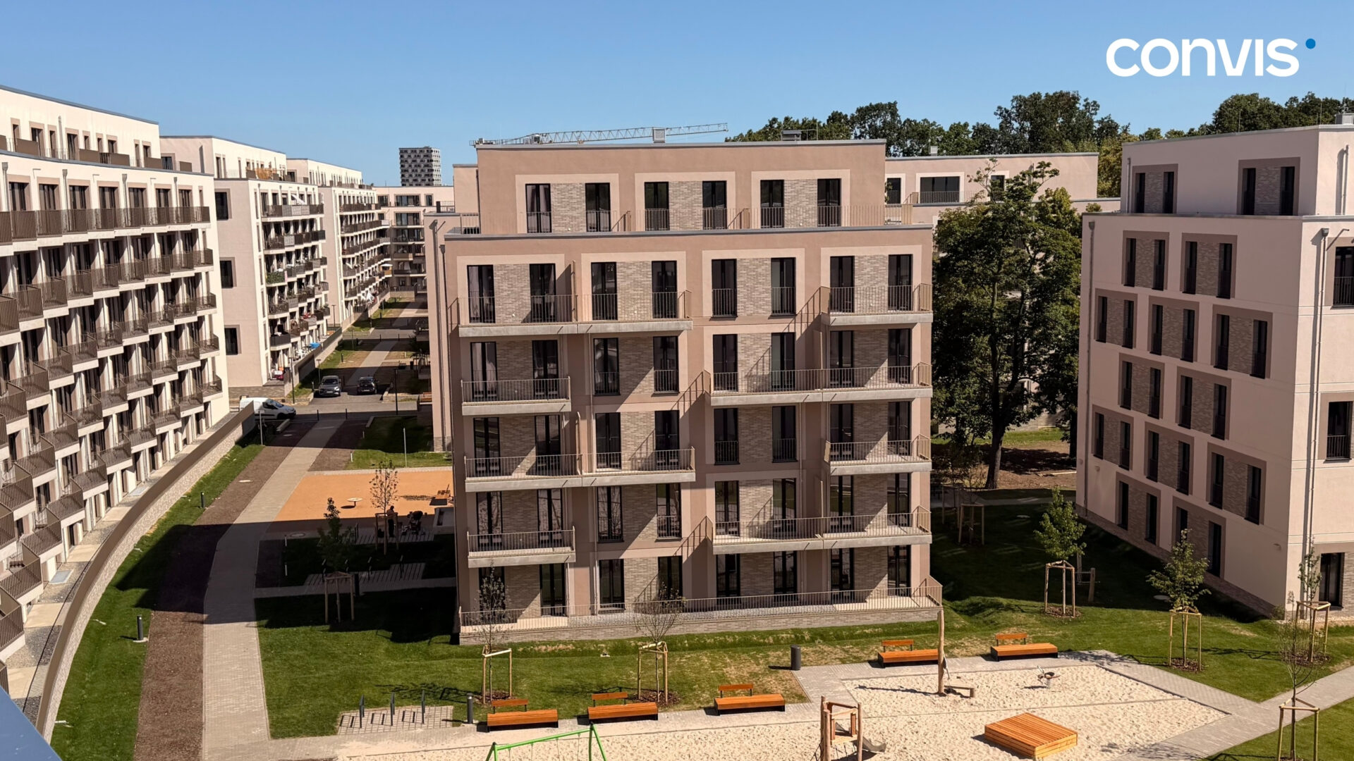 Moderne Wohnanlage mit Grünflächen und Spielplatz in urbaner Umgebung.