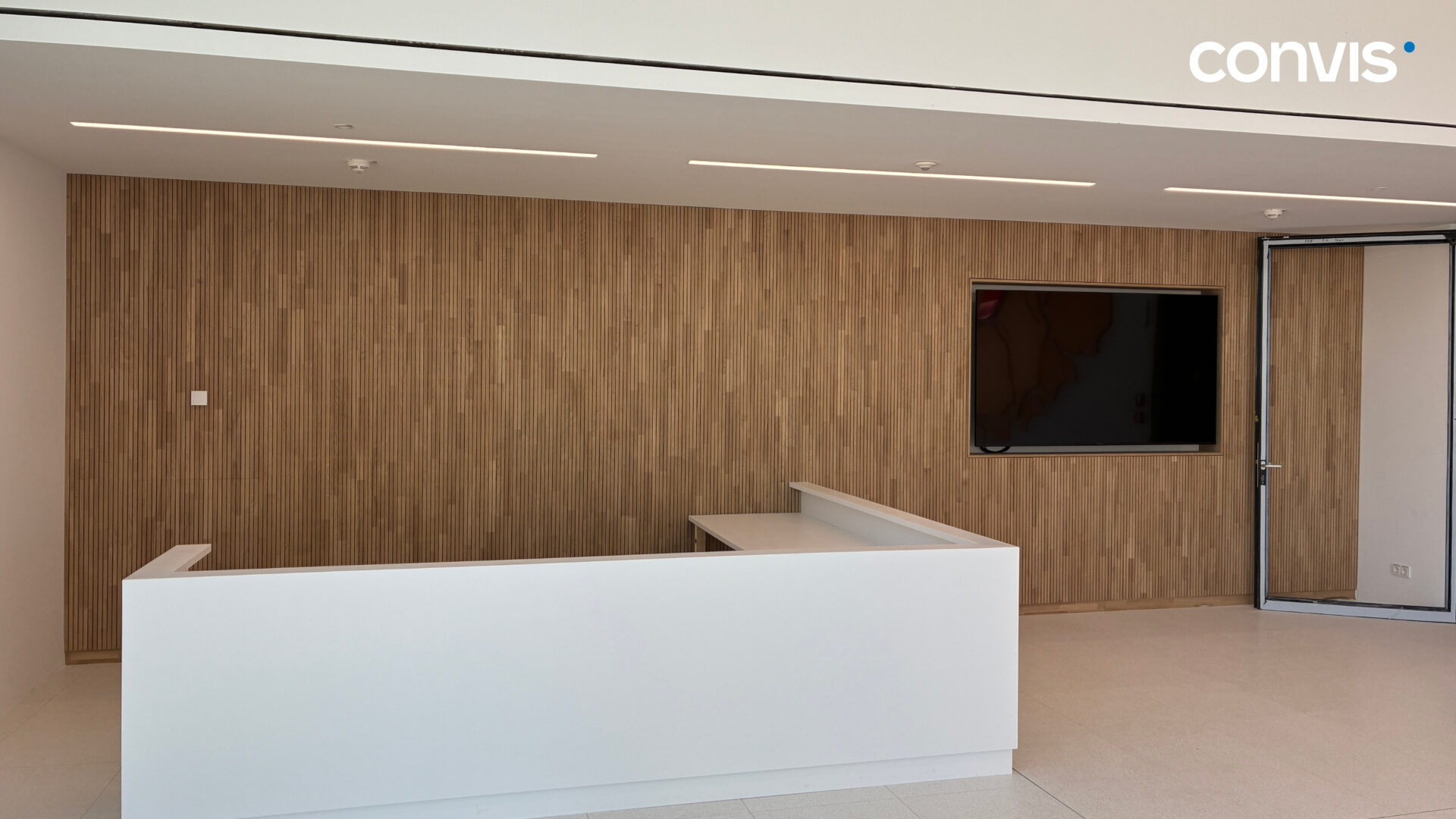 Moderne Empfangstheke mit Holzverkleidung und TV in einem hellen Büro.