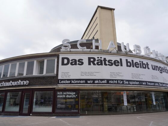 Gebäuder des Theaters Schaubühne Berlin: Plakat mit dem Text "Das Rätsel bleibt ungelöst" am Gebäude.