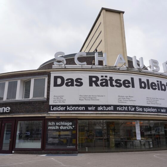 Gebäuder des Theaters Schaubühne Berlin: Plakat mit dem Text "Das Rätsel bleibt ungelöst" am Gebäude.