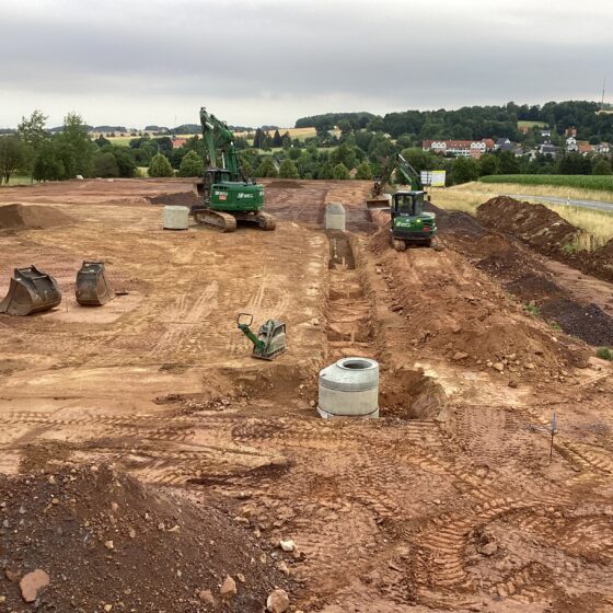 Bauplatz mit Baggern und Erdarbeiten in ländlicher Umgebung.