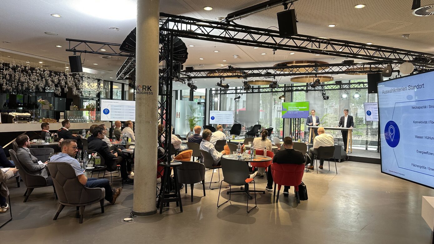 Konferenzraum mit Präsentation und Publikum, moderne Einrichtung und Networking-Atmosphäre.