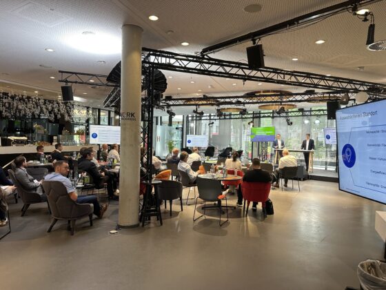 Konferenzraum mit Präsentation und Publikum, moderne Einrichtung und Networking-Atmosphäre.