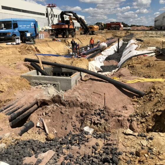 Bauarbeiten für die Logistikhalle in Hainichen mit Maschinen und Rohren auf einer Baustelle im Freien.