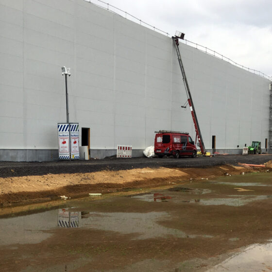 Bau einer Lagerhalle (Logistikhalle in Hainichen) mit Gerüst und Baumaschinen in einer Baustellenumgebung.
