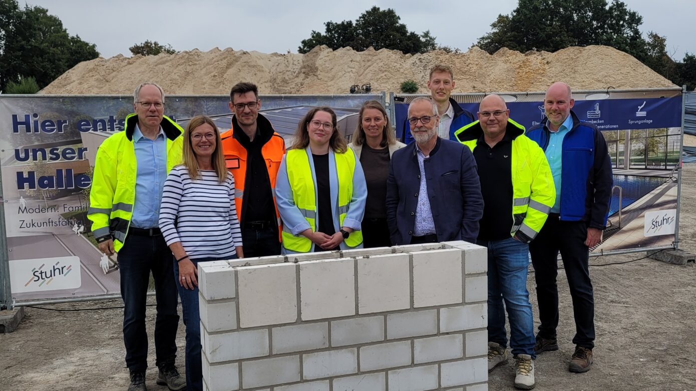 Grundsteinlegung für neue Halle: Teamfoto mit Bauleitern und Beteiligten in Sicherheitskleidung.