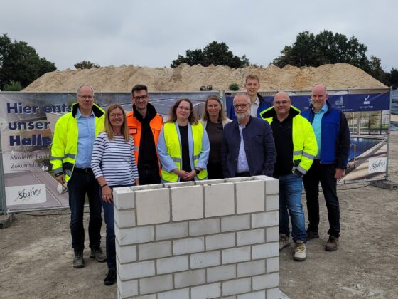 Grundsteinlegung für neue Halle: Teamfoto mit Bauleitern und Beteiligten in Sicherheitskleidung.