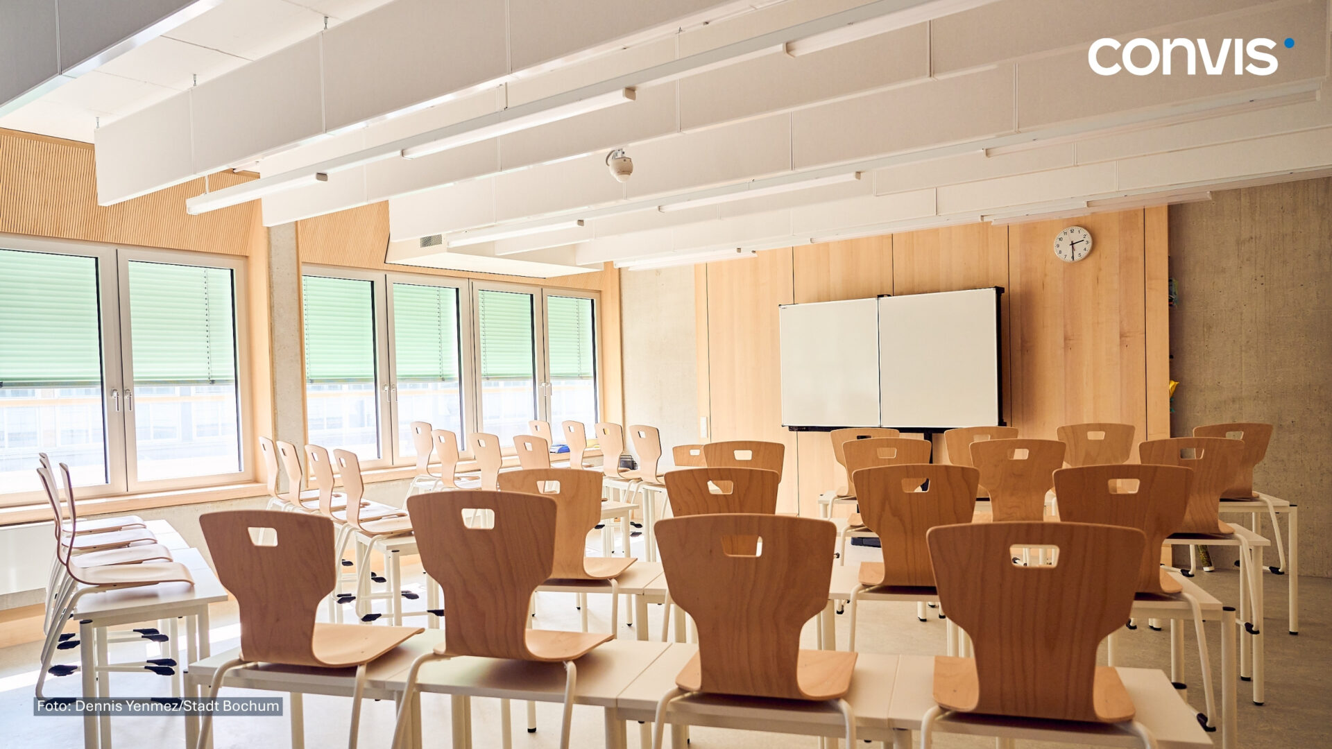 Moderne Schulklasse mit Holzstühlen, großen Fenstern und Whiteboard für effektives Lernen.