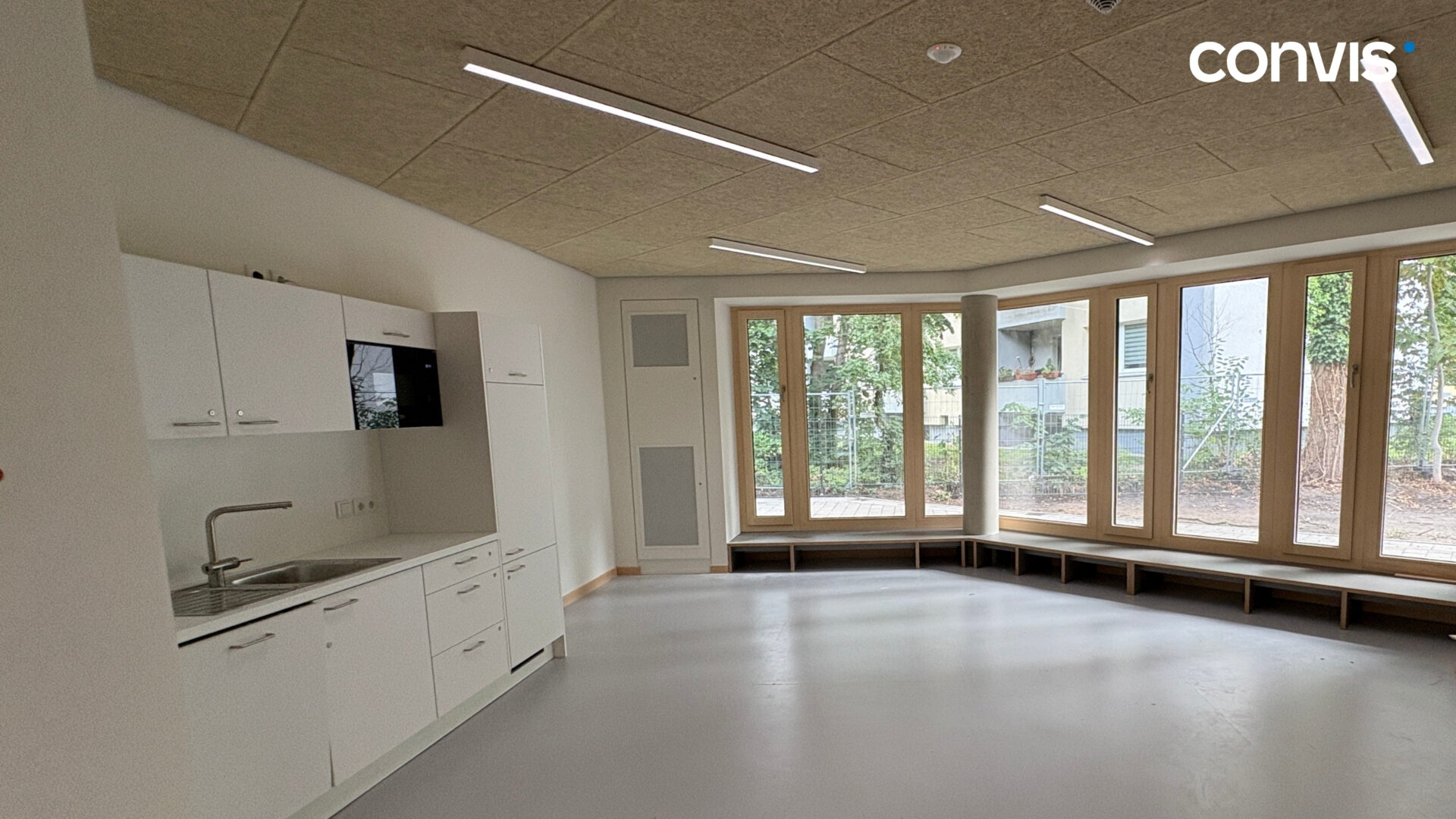 Moderne Küchenzeile in einem lichtdurchfluteten Raum mit großen Fenstern.