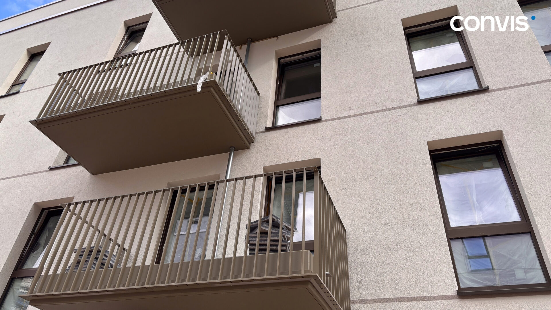 Moderne Wohnanlage mit Balkonen und großen Fenstern in neutralen Farben.