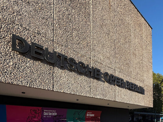 Fassade der Deutschen Oper Berlin mit modernem Design und buntem Plakat.