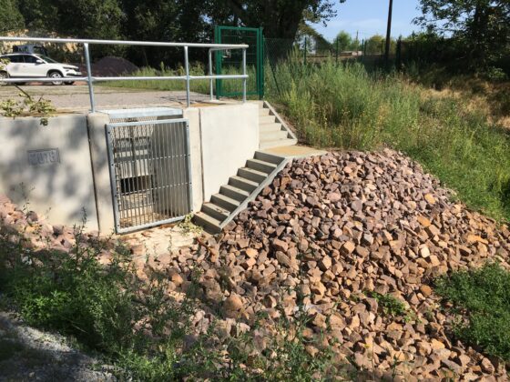 Zugang zu einem Gelände mit Treppe und Steinhaufen neben einem Gittertor.